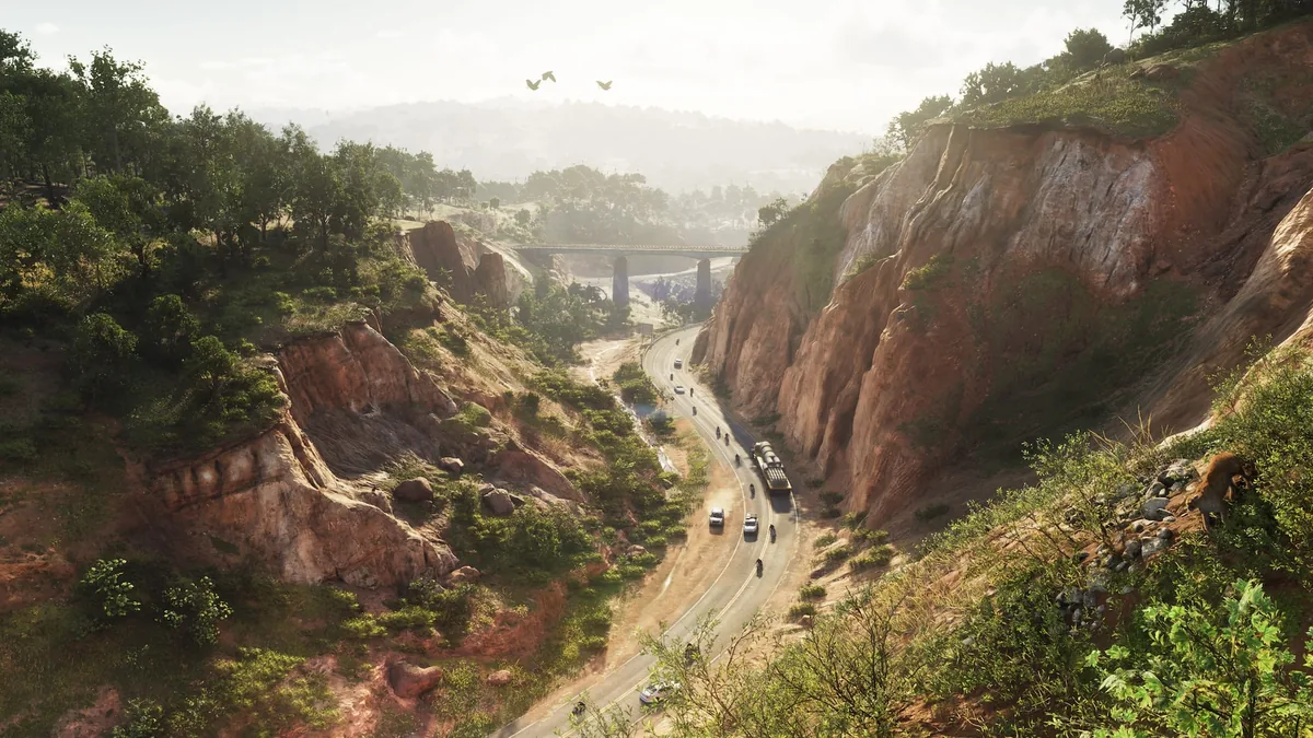 A winding road between two red rock cliffs in Mount Kalaga National Park with cars and bikes on it and a bridge in the distance, official GTA 6 screenshot