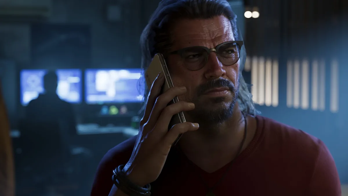 Raul Bautista on the phone in a dark room lit by computer monitors, official GTA 6 screenshot